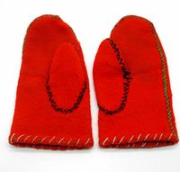 Pair of red felt gloves showing black stitching around the thumbs and white and green blanket stitch edging, laid flat with palms down.