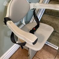 Seat unit with beige vinyl padded seat, armrests, seatbelt, folded footrest