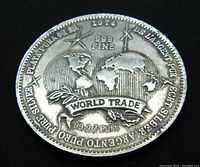 Obverse side of silver coin showing world map with 99.9% pure silver markings and inscriptions in multiple languages.