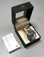 Watch with stainless steel bracelet seated in Victorinox presentation box alongside instruction booklet