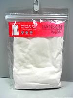 Photo of the front of packaged Danskin Warm System Technology long sleeve tee, size XL, showing folded white shirt inside clear resealable plastic packaging with a red label.