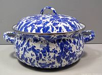 Front view of closed mini Dutch oven showing blue swirl enamel pattern with handles and lid.