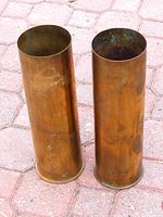 Two brass shell casings standing upright on paving stones