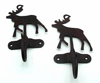 Two iron moose-shaped hooks with mounting bases and single curved hooks shown from the front against a white background, showing slight rust and forged details.