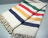 Full view of folded vintage Hudson Bay trapper stripe throw blanket showing the colored stripes and fringed edge.