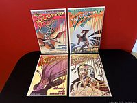 Four Blood of Innocent comic books laid out in two rows on a black surface against a red background. Each comic features detailed horror-themed cover artwork.