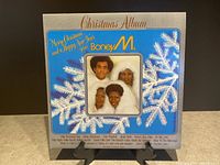 Front cover of Boney M. Christmas Album vinyl record showing snowflake design and band member photo.