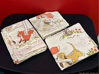 Multiple folded bedding pieces showing Fox and the Hound characters and natural outdoor scenes printed in color on fabric.