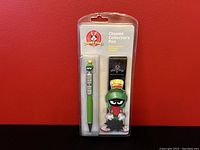 Front view of the packaged Looney Tunes Marvin the Martian Chrome Collector's Pen showing the pen with character topper and pouch inside blister pack