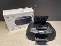 Sony CFD-ST0 black portable boombox with CD open lid, cassette door open, and antenna extended next to its original box.