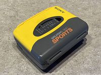 Yellow and gray Sony Walkman Sports WM-SXF 10 cassette player with visible AM/FM radio tuner window on top surface.