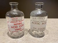 Front view of both vintage Pyrex acid bottles side by side showing labels Nitric Acid Con. HNO3 and Acetic Acid CH3COOH