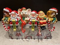 Photo of all six vintage plastic Christmas mantle hangers arranged on a holiday patterned box.