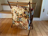 Sewing basket side view showing floral fabric panel and wooden stand on hardwood floor.
