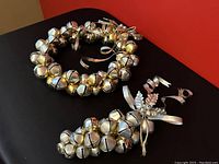 Full view of the silver and brass sleigh bell wreath and matching distribution of bells cluster on black background.