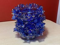 Stack of four cobalt blue glass dessert bowls showing the ruffled edges and painted gold accents.