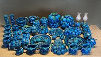 Wide view of all blue fruit motif ceramic pieces arranged on a neutral surface