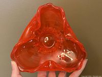 Top view showing the triangular shape with ruffled edge and glossy orange translucent glass.