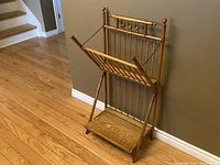 Victorian oak periodical stand angled view showing rack and shelf against wall on hardwood floor