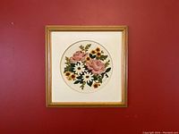 Frontal view of the framed crewel floral needlepoint artwork showing the full circle floral design and wooden frame.
