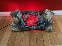 Front view of the vintage electric fireplace insert showing the birch log design and glowing red light inside simulating embers.