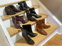 Photo of all 8 pairs of women's ankle boots arranged on staircase, showing colors and styles clearly.