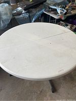 Photo showing the full round folding table top, white plastic with minor marks.