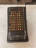 Front side view showing multiple rows of number keys and crank handle.