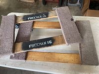Top view of one wooden furniture dolly showing carpet padding and Freeman 16 marking on wooden slats
