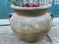 Front view of wide, round decorative pot with handles and weathered brown finish, showing texture and age wear.