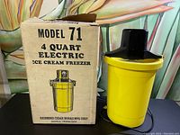 Photo showing the Model 71 electric ice cream freezer unit next to its original box with product illustration and labeling.