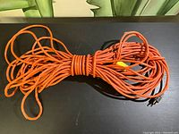 Full coiled view of orange extension cord on a black surface