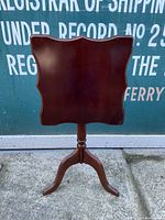 Front view of folding top vintage wooden end table showing dark polished wooden scalloped tabletop with smooth finish and pedestal base.