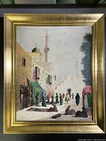Front view of the framed painting depicting Middle Eastern street scene with people, architecture, and minaret under bright sky.