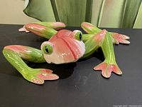 Front view of glossy ceramic frog ornament showing detailed paint and large eyes.