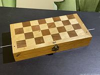Closed wooden folding chess board with latch secures it closed