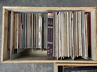 Top-down view of the wooden box showing many LP and 45 RPM records vertically stored inside.