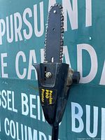 Close-up photo of the Poulan Pro Pruner chainsaw extension blade and housing with visible brand label and some rust on the chain.