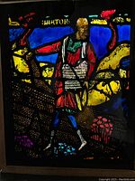 Close-up of stained glass miniature showing a man with basket in vibrant colors.