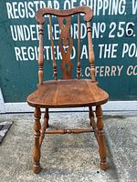 Front view of vintage wooden chair showing carved backrest and turned legs.
