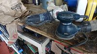 Showing Mastercraft angle grinder and Black & Decker palm sander on workshop surface