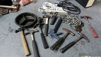 Wide view of assortment showing hammers, chains, cords, tray, and tool grip arranged on floor.