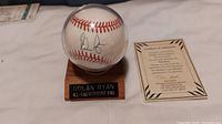 Autographed baseball displayed in protective case with wooden base and certificate of authenticity beside it