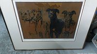 Framed silkscreen print featuring four dogs in black lines, brown background, white mat, in simple frame.