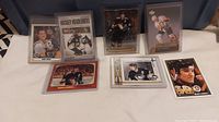 Seven Mario Lemieux hockey cards arranged in two rows on white surface; cards show different images of Lemieux in Penguins uniform in protective sleeves and cases.