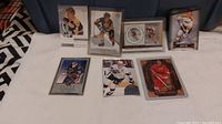 Front view of eight hockey cards featuring Bobby Orr, Gordie Howe, Wayne Gretzky, others, displayed on white cloth surface