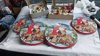Five round decorative Christmas tins featuring colorful vintage Santa and woodland animal illustrations and rims painted red.