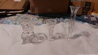 Four vintage clear crystal vases placed side by side showing variation in height and shape