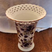 Front view of purple pansy decorated porcelain vase showing hand-painted flowers and pierced lattice rim with gold trim.