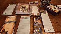 Photo showing multiple floral themed stationery items, including notepads, sticky notes, note cards, and spiral-bound notebook, all sealed and new.